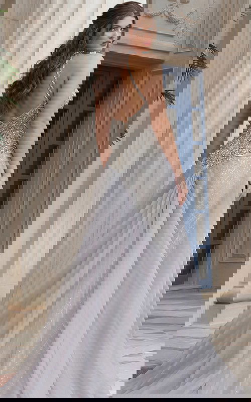 Back view of beaded halter style dress with open back, fitted waist, and flowing sheer overskir